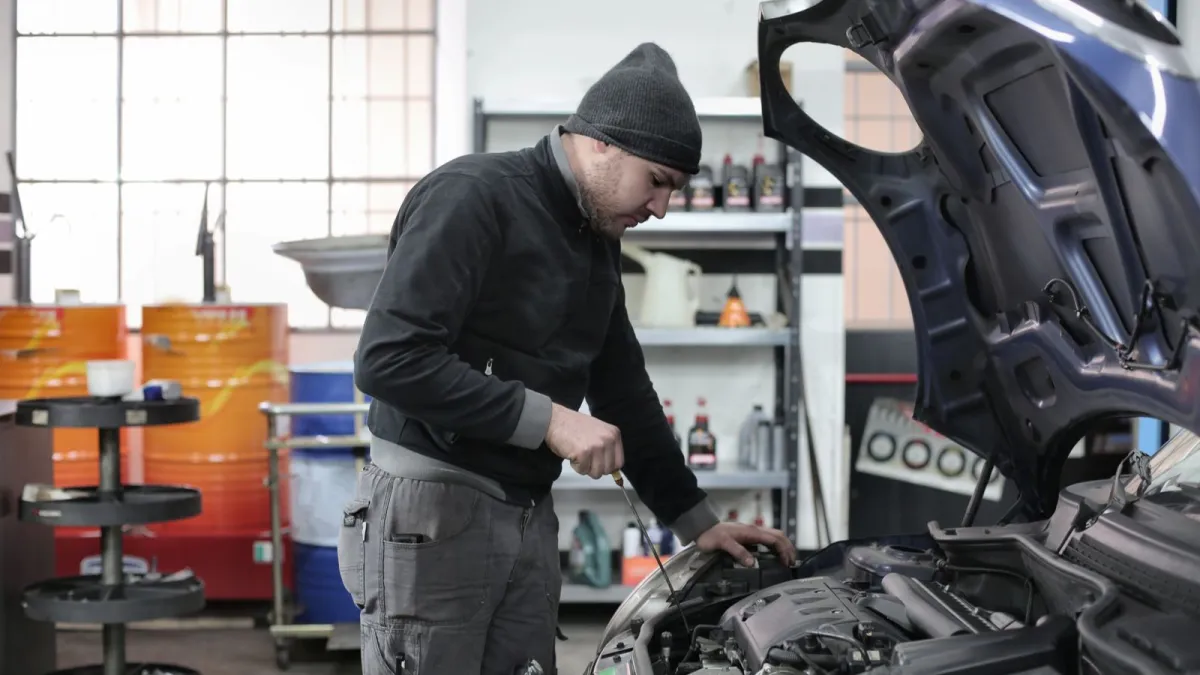 A mechanic checking the dipstick under an open bonnet
