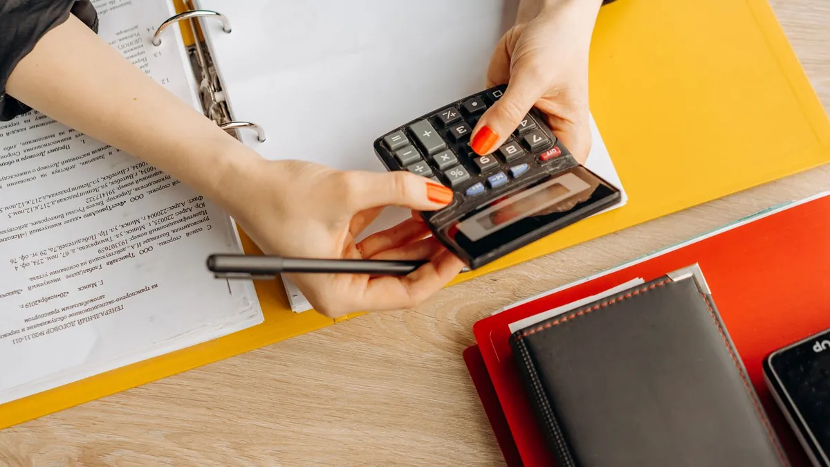 A person working through loan paperwork with a calculator