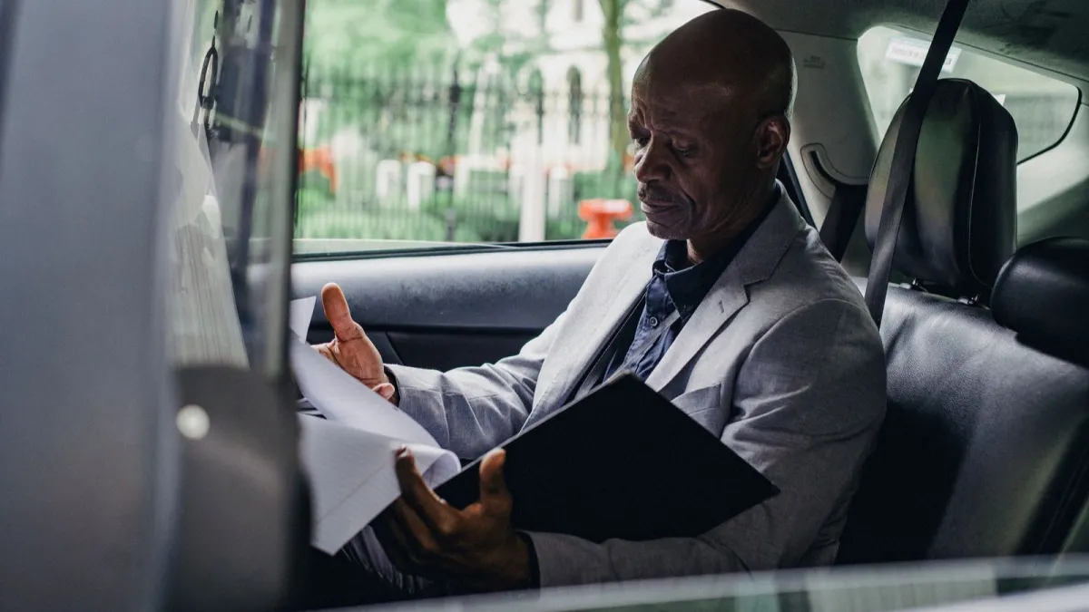 A man reading a document in the back seat of a car