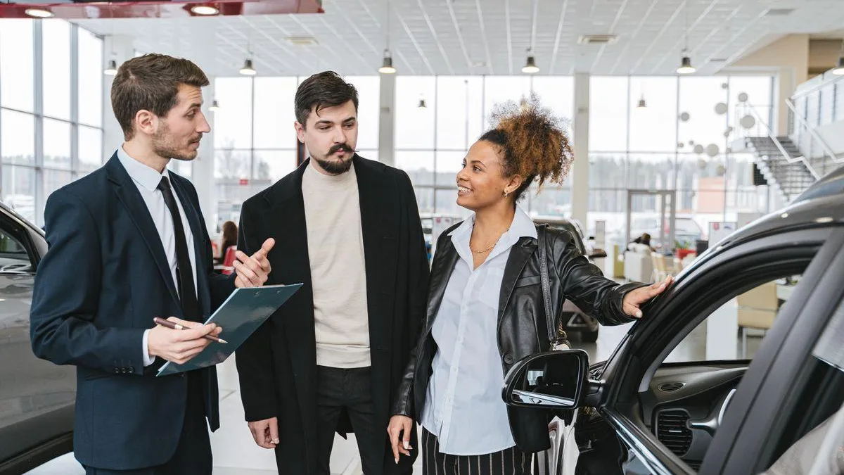 Vehicle consultant with clipboard discussing vehicle history and inspection with buyers